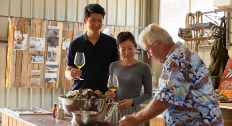 格林威尔角吉姆·怀尔德牡蛎店 (Jim Wild's Oysters) 的一对夫妇与吉姆·怀尔德 (Jim Wild) 一起享用新鲜开封的牡蛎