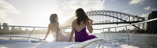 两名女士坐在游艇船头在悉尼港 (Sydney Harbour) 航行
